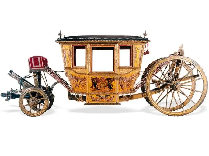 Un carrosse doré et sculpté de la collection du Museu Nacional dos Coches, sur fond blanc