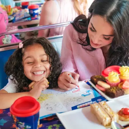 Une mère et sa fille jouent à la mission Pat' Patrouille à bord du bus, avec le goûter sur la table